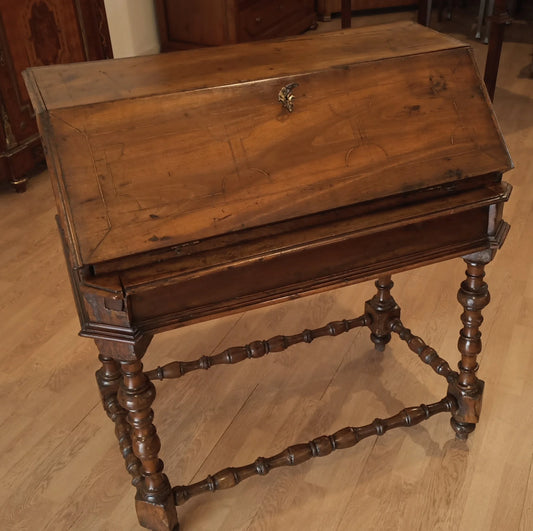 Escritorio antiguo de madera del siglo XVIII con alas abatibles, patas torneadas y superficie de escritura inclinada.
