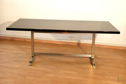 Tavolo rettangolare moderno con piano in vetro nero e gambe in metallo cromato disegnato da gianni moscatelli